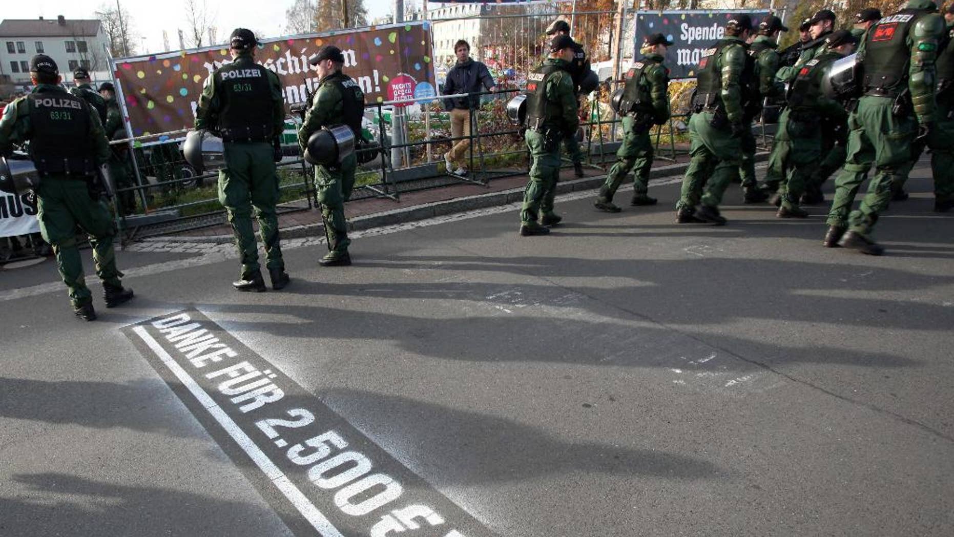 In this picture taken Saturday, Nov. 15, 2014, police stand in front of banners reading "Donate with every step, march", top left, and "#right against right" top right, during a far-right march Wunsiedel, southern Germany. Letters on the ground say "Thanks for euro 2,500!". After failing to prevent neo-Nazis from staging an annual pilgrimage to the birthplace of Adolf Hitler’s deputy Rudolf Hess, the Bavarian town decided to change tack this year. Residents and businesses pledged to pay 10 euro (US dollar 12.50) for every meter the neo-Nazis walked, and motivational signs were erected along the route of Saturday’s march. Inge Schuster, a spokeswoman for the town, said Tuesday that the stunt received “a great response,” raising more than 10,000 euros for the group EXIT-Deutschland that helps people leave the neo-Nazi scene. (AP Photo/dpa, Fricke)