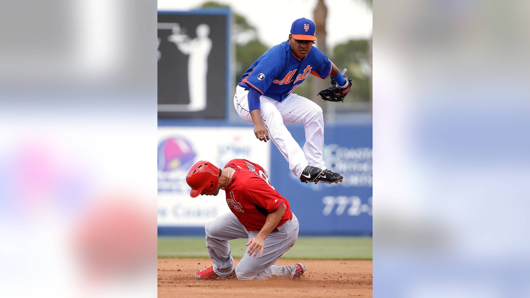 New York Mets shortstop Ruben Tejada, top, jumps over St. Louis Cardinals' Randal Grichuk after throwing to first base for a double play in the second inning of an exhibition spring training baseball game, Wednesday, March 12, 2014, in Port St. Lucie, Fla. (AP Photo/David Goldman)