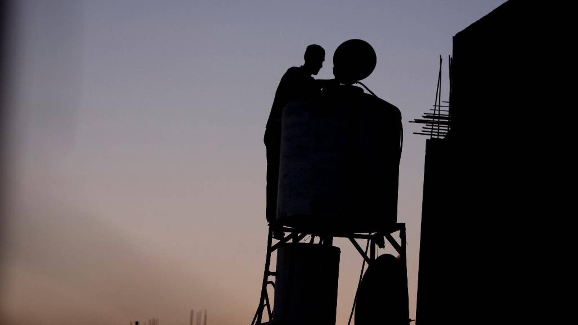 In this Saturday, June 18, 2016 photo, a Palestinian man checks the water tank on the roof of his home after water supply was cut in the village of Salem near the West Bank city of Nablus. Palestinians in the West Bank have long faced shortages of water in the summer months. But this year, as they fast dawn-to-dusk amid scorching heat during the Muslim holy month of Ramadan, many villagers in the north of the territory say Israel has intentionally cut the water flow to their taps. (AP Photo/ Majdi Mohammed)