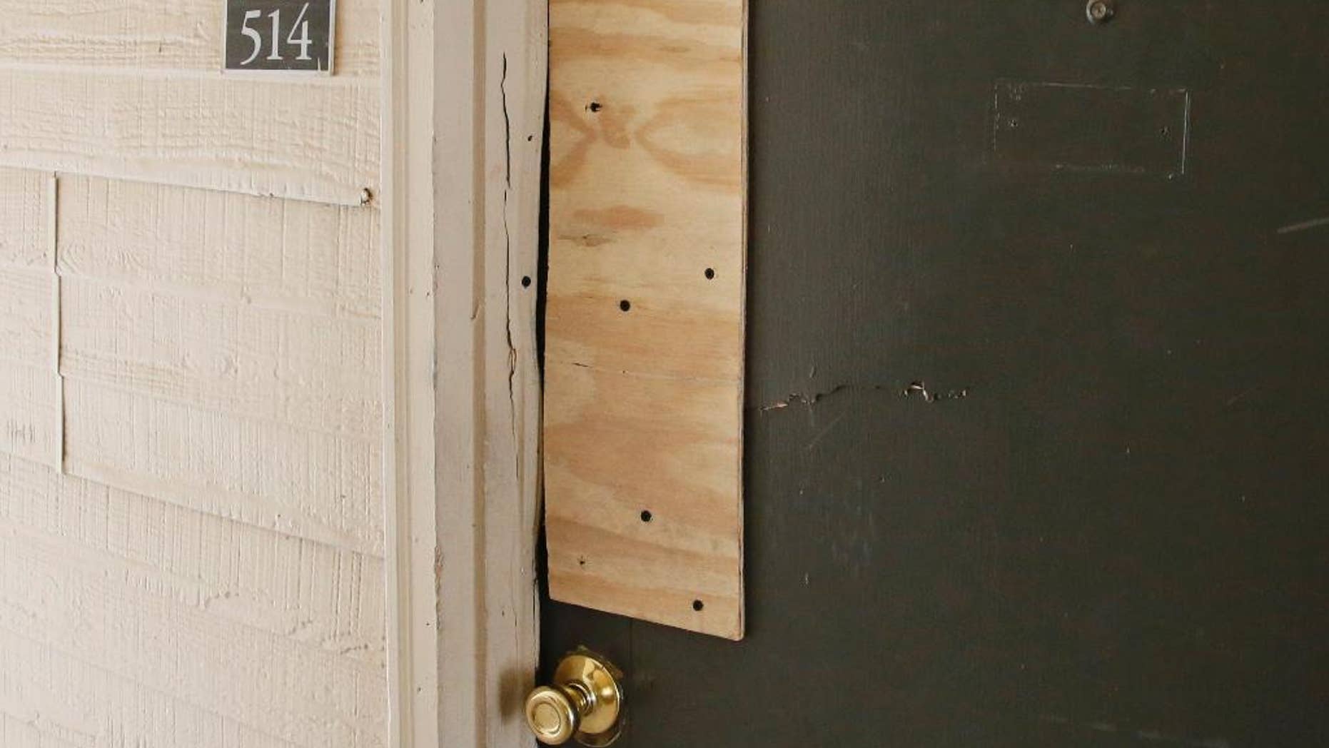 The boarded-up door of an apartment where Oklahoma City police have arrested a mother on suspicion of stabbing a man and her two children, the youngest of which was pronounced dead when police arrived on scene, is pictured in Oklahoma City, Monday, July 11, 2016. (AP Photo/Sue Ogrocki)
