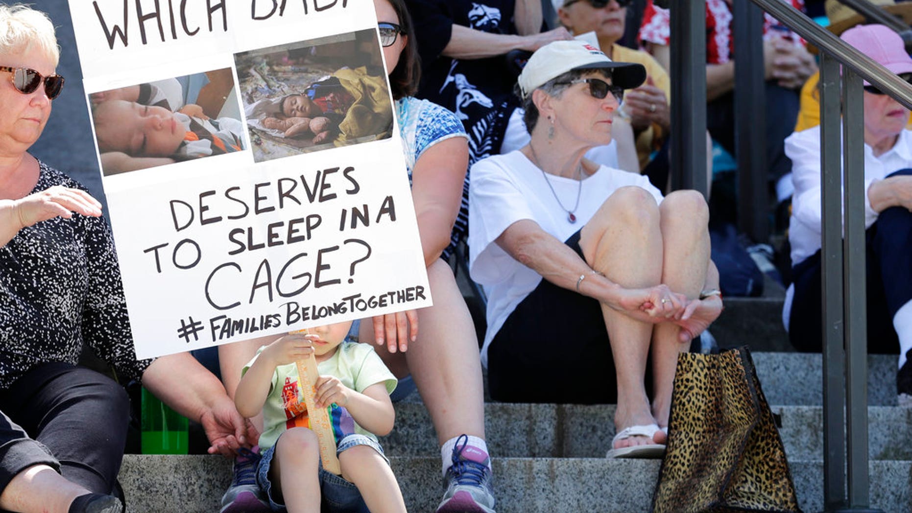 Christopher Baker, 3, holds a sign that reads "Which baby deserves to sleep in a cage?" as he attends a Poor People's Campaign rally with his mother, Katie Baker, behind sign, Monday, June 18, 2018, at the Capitol in Olympia, Wash. U.S. President Donald Trump defended his administration's border-protection policies Monday in the face of rising national outrage over the forced separation of migrant children from their parents. (AP Photo/Ted S. Warren)