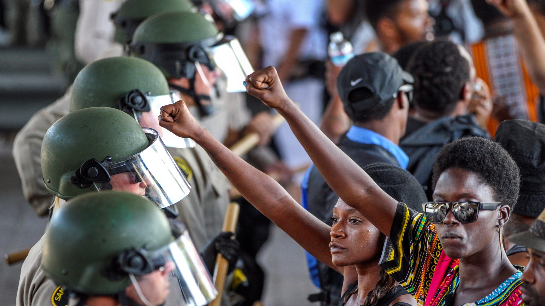 Ebonay Lee, center, and another unidentified woman hold up their fists during a demonstration in front of police on Sept. 28. in El Cajon, Calif.