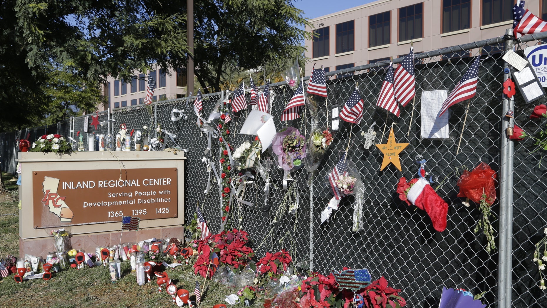 Photos, flowers and American flags honoring the victims of the San Bernardino terror attack hang outside the Inland Regional Center where the fatal shooting took place.
