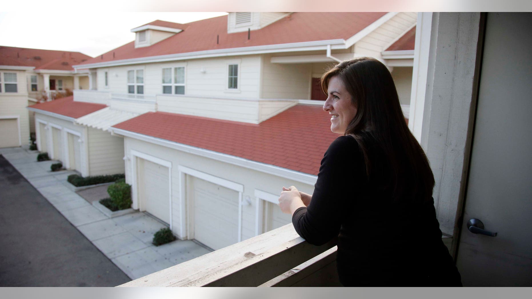 In this Dec. 11, 2015, photo, Katy Howser, a kindergarten teacher in the Santa Clara School District, looks out from the balcony of her apartment at Casa Del Maestro, an apartment complex for teachers, in Santa Clara, Calif. School districts in high cost-of-living areas and rural communities that have long struggled to staff classrooms are considering buying or building rent-subsidized apartments as a way to attract and retain teachers amid concerns of a looming shortage. (AP Photo/Marcio Jose Sanchez)