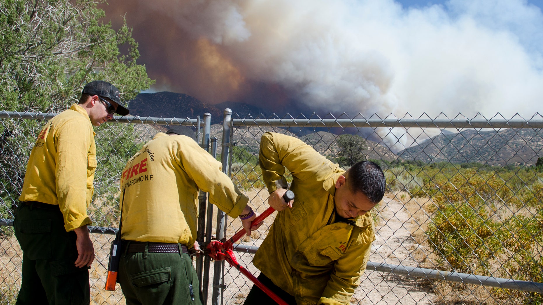 U.S. Forest Service firefighters break a lock on a gate while battling a wildfire.