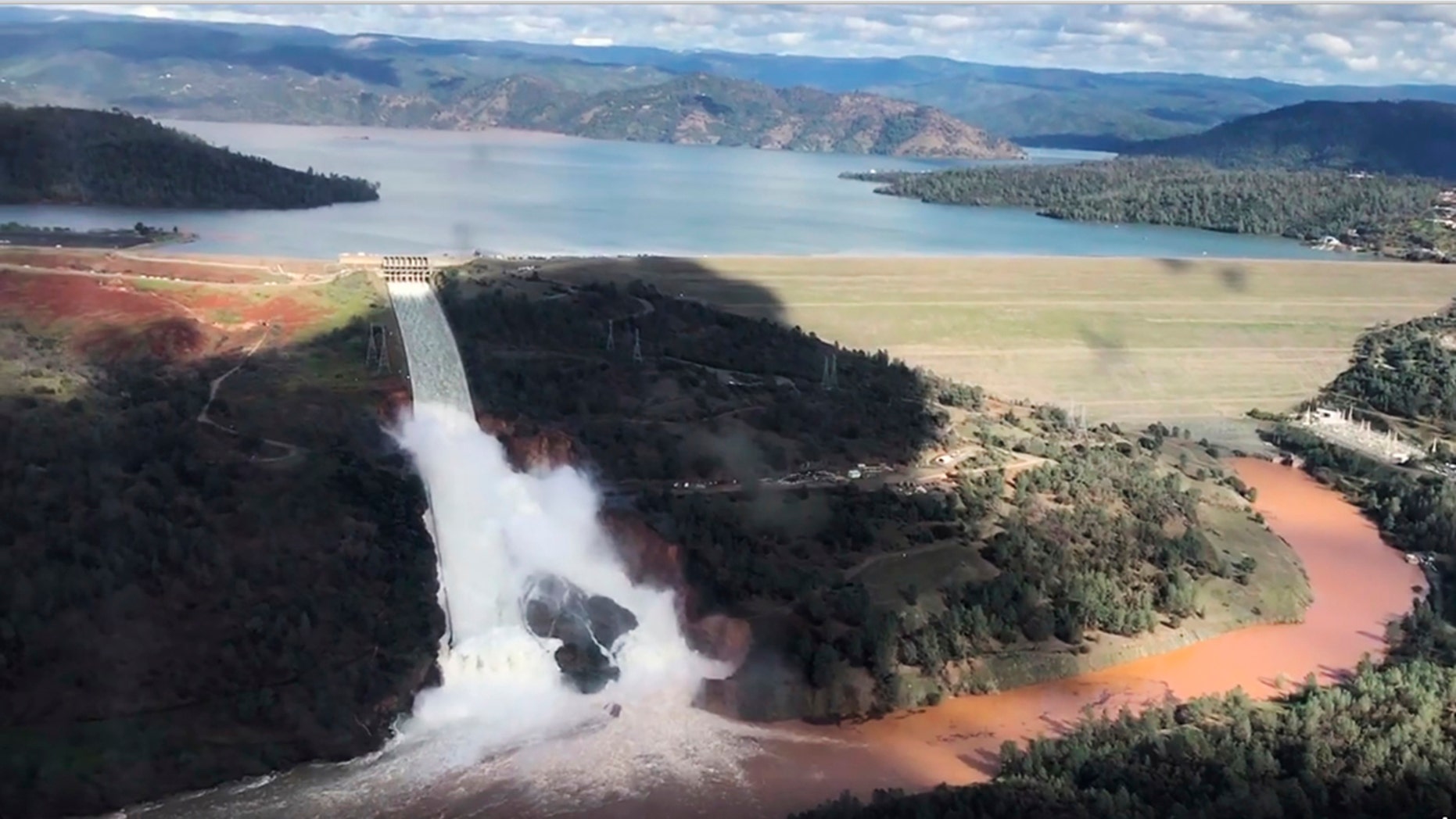 Feb. 10, 2017: This image from video provided by the office of Assemblyman Brian Dahle shows water flowing over an emergency spillway of the Oroville Dam in Oroville, Calif., during a helicopter tour by the Butte County Sheriff's office.