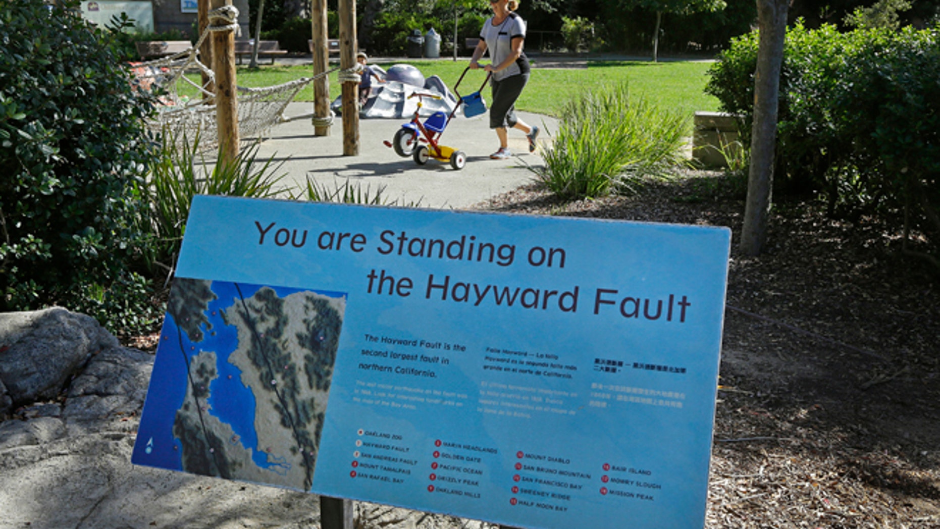 In this Tuesday, Oct. 18, 2016 photo, a sign notifying people they are standing on the Hayward Fault stands at the children's zoo area at the Oakland Zoo in Oakland, Calif.