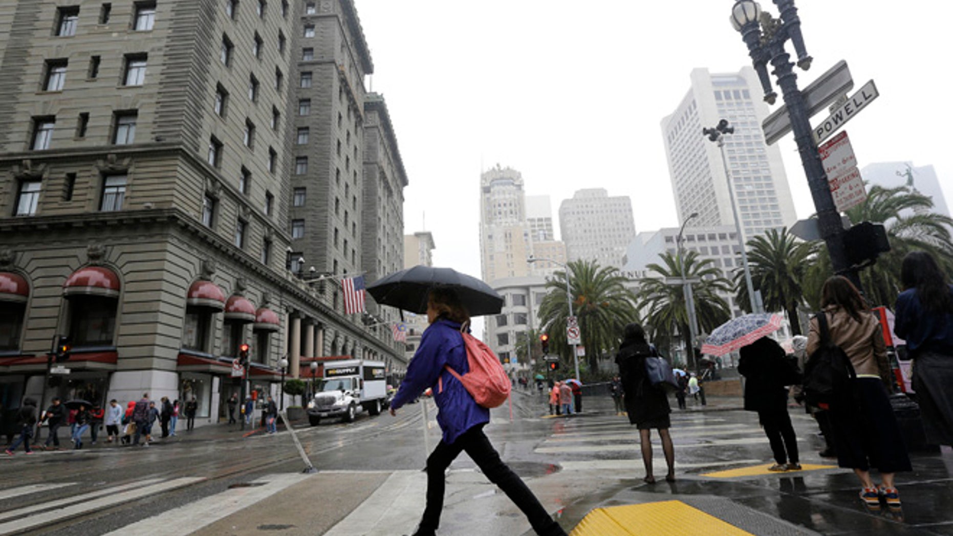 A woman carries an umbrella as she crosses Powell Street n San Francisco, Thursday, March 3, 2016. Light rain has started in the San Francisco Bay Area as the region braces for a series of storms expected this weekend and into next week. (AP Photo/Jeff Chiu)