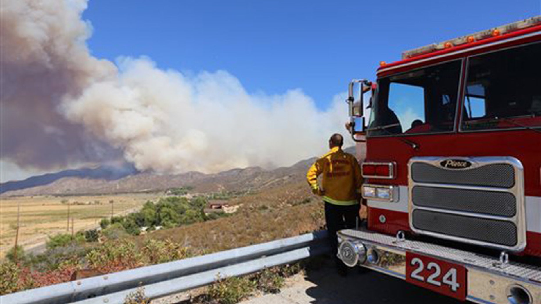 A San Bernardino County Fire Department engine and its crew keep watch over Summit Valley, Calif., as a wildfire burns east of Silverwood Lake on Sunday, Aug. 7, 2016.