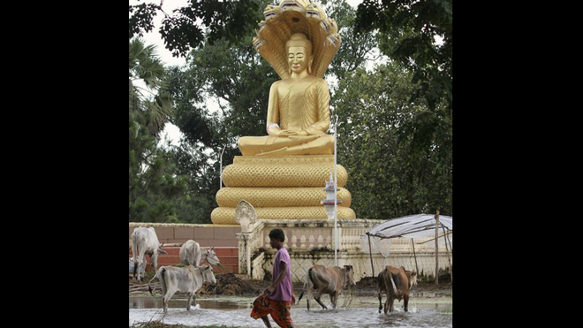 Oct. 13, 2011: A boy walks in flood waters past a Buddha statue in Kampong Thom province.