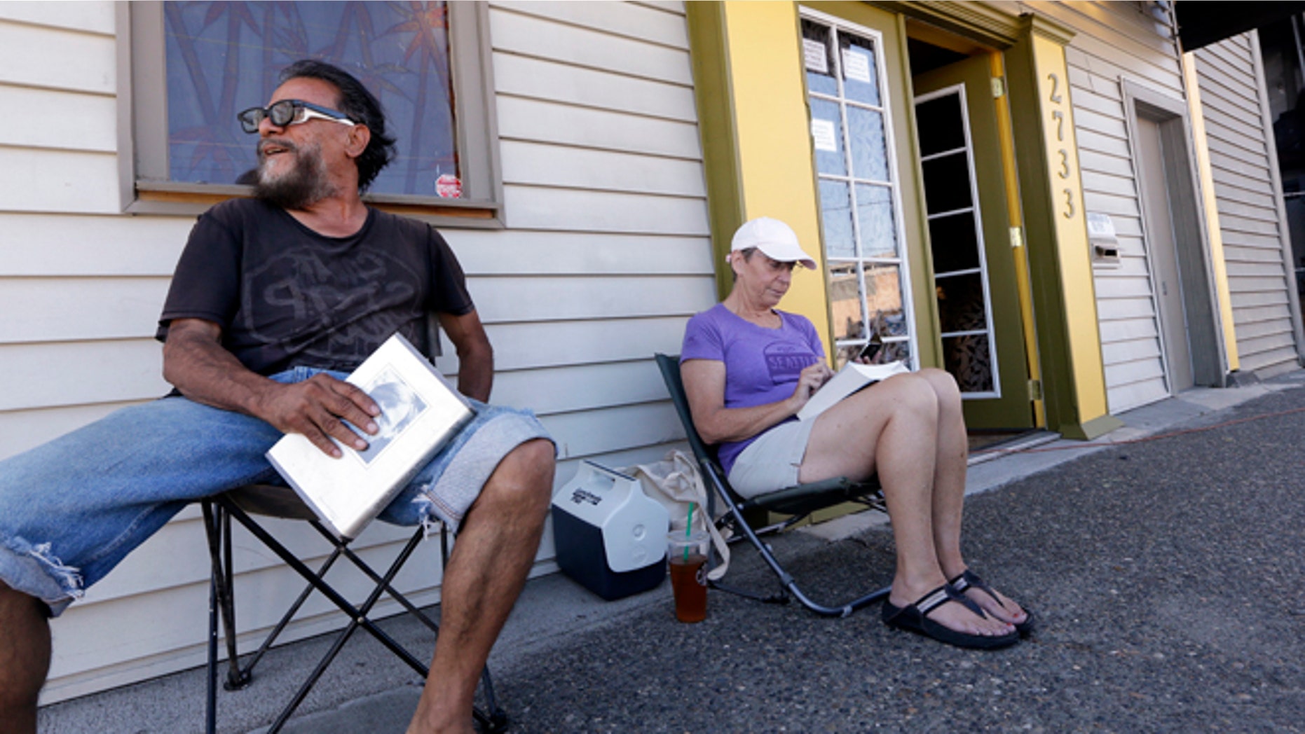 July 7, 2014: George Vargas, left, takes a seat next to first-in-line customer Deb Greene in front of the recreational marijuana store Cannabis City in Seattle. The store will be the first and only store initially in Seattle to legally sell recreational pot when sales begin Tuesday.
