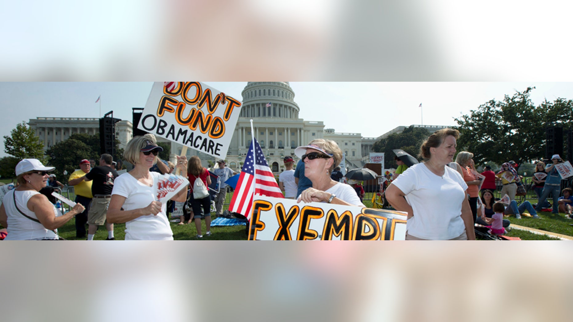 FILE -- Sept. 10, 2013: Linda Norman, right, and Joanna Galt, both from Florida, hold their banners during a "Exempt America from Obamacare" rally on the West Lawn of the Capitol in Washington.