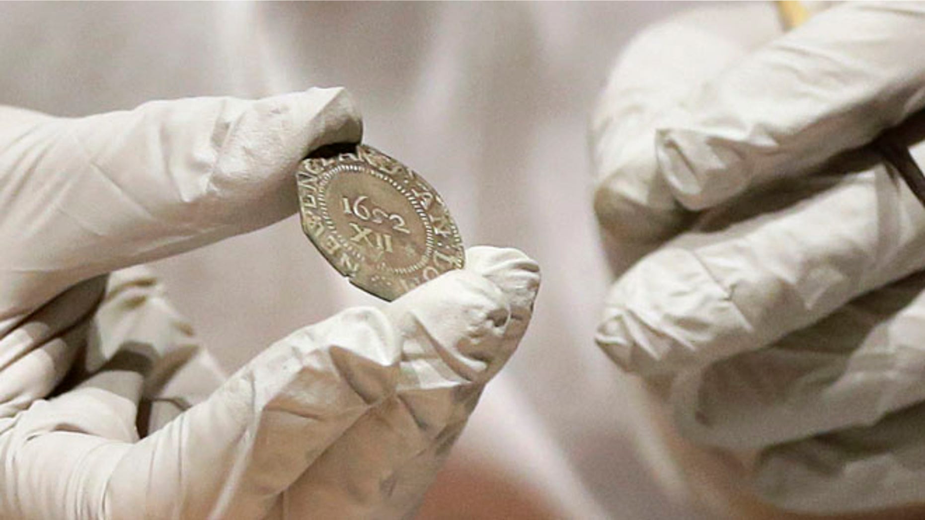 Jan 6. 2015: Museum of Fine Arts Boston Head of Objects Conservation Pam Hatchfield displays a coin as she removes it from a time capsule at the museum in Boston. (AP)