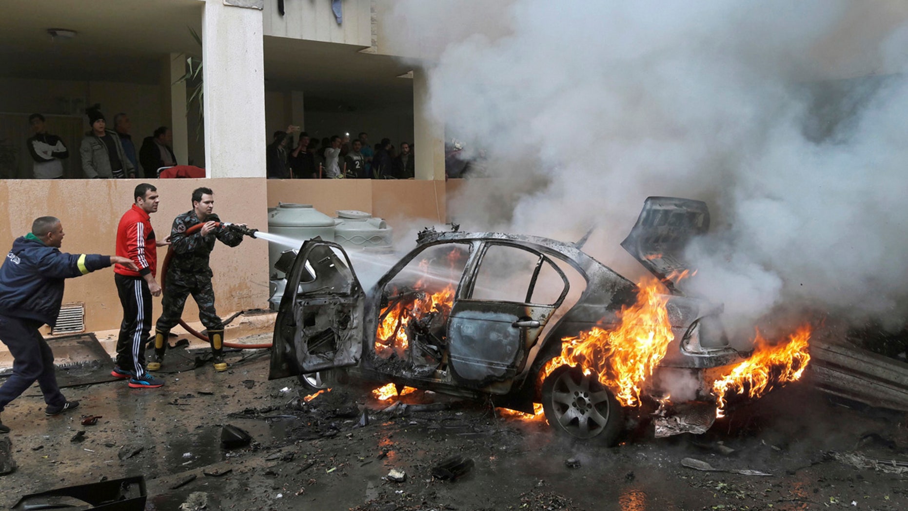 Firefighters extinguish a burning car that was destroyed in a bombing in the southern port city of Sidon, Lebanon, Sunday, Jan. 14, 2018