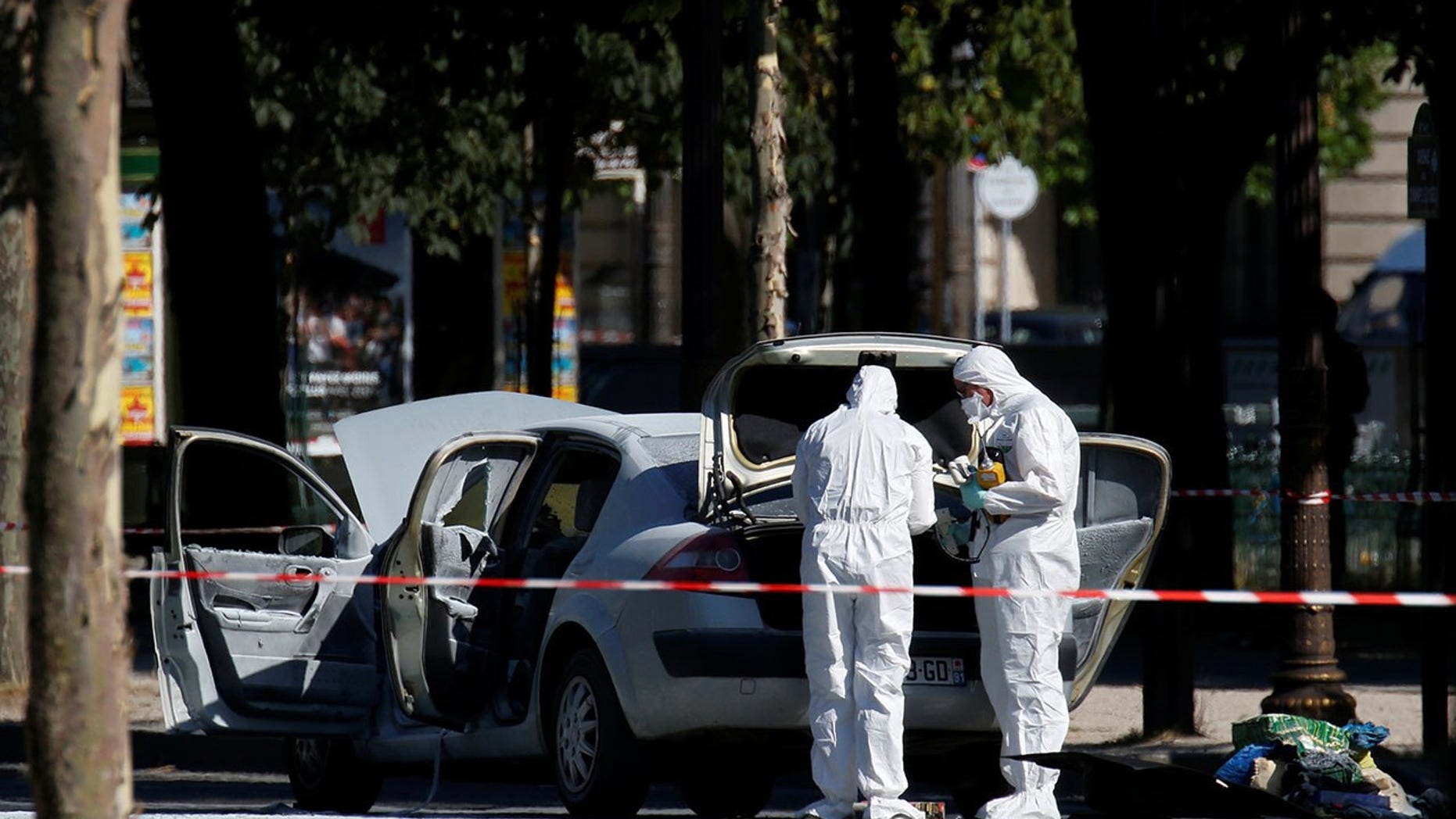 Members of the scientific police inspect a burned car at the scene of an incident in which a car rammed a gendarmerie van on the Champs-Elysees in Pairs, France, June 19, 2017. (REUTERS/Gonzalo Fuentes)