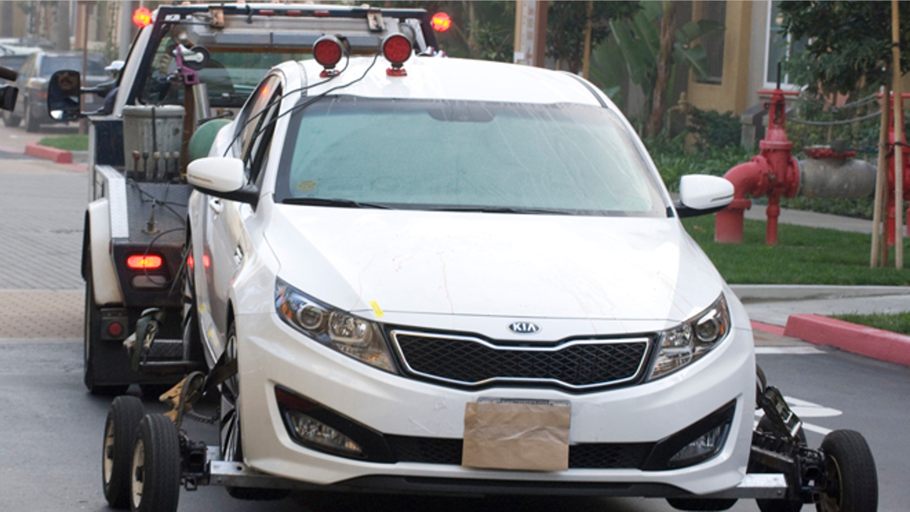 Feb. 3, 2013: A police tow truck removes a Kia sedan from the property where two people were found shot to death inside a parked car, Sunday night, in the parking structure of a condo complex in Irvine, Calif. Police in Orange County say they have no motive for a shooting that killed California State University, Fullerton assistant college basketball coach Monica Quan and her fiance, Keith Lawrence, whose bodies were found in a parked car.