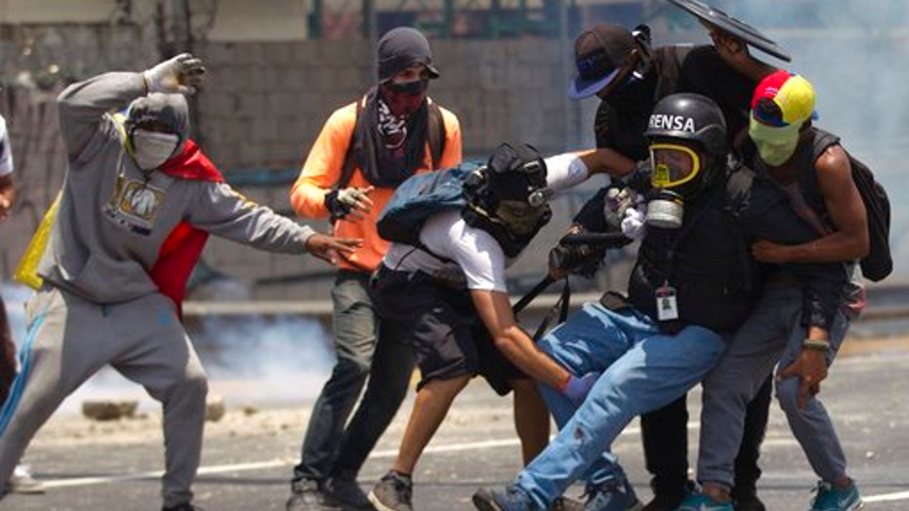 Demonstrators help a journalist who was injured in a leg while covering clashes between demonstrators and the Bolivarian National Guard during a protest in Caracas, Venezuela, Monday, April 10, 2017.