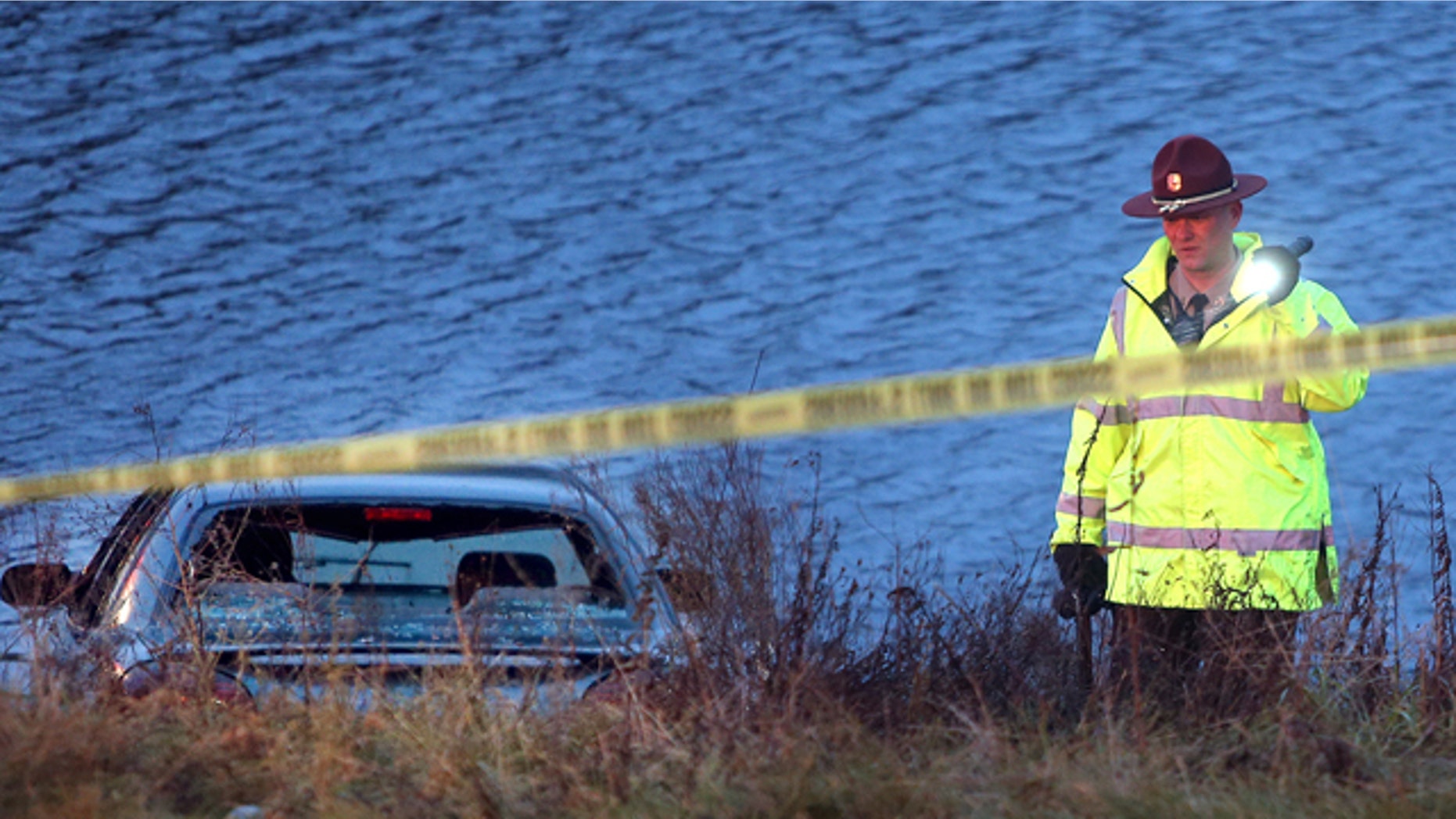 Nov. 21, 2013: A police officer investigates the scene where six people were rescued after their car went into a holding pond near a highway exit ramp.