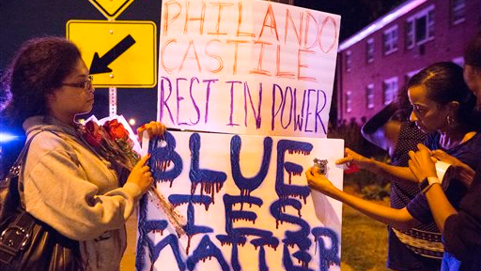 Protester's hang signs on a post near the scene of Philando Castile's shooting in Falcon Heights, Minn., Thursday, July 7, 2016. Castile was shot in a car Wednesday night in the largely middle-class St. Paul suburb of Falcon Heights. Police have said the incident began when an officer initiated a traffic stop in suburban Falcon Heights but have not further explained what led to the shooting. .(Leila Navidi/Star Tribune via AP)