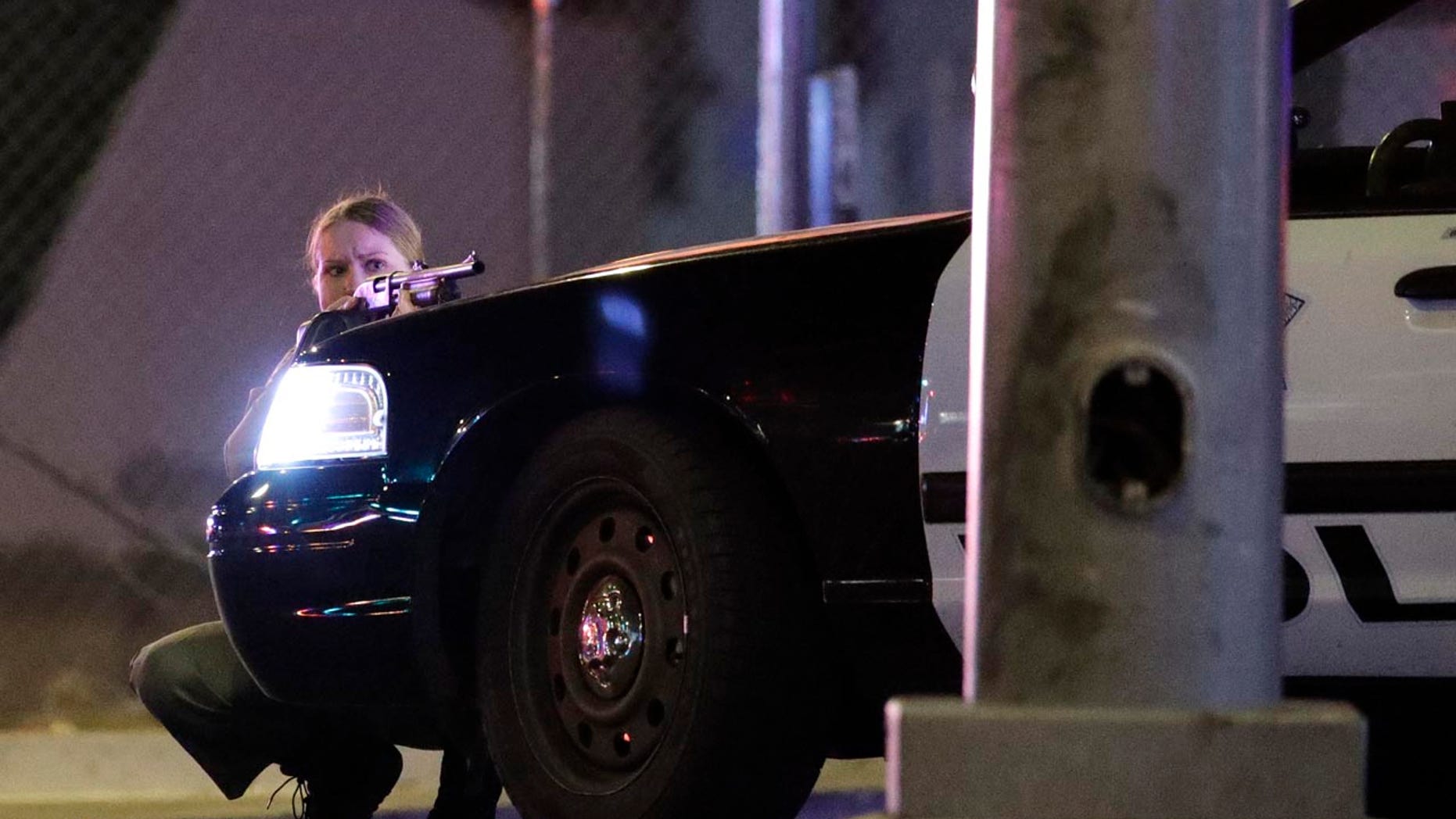 A police officer takes cover behind a police vehicle during a shooting near the Mandalay Bay resort and casino on the Las Vegas Strip, Sunday, Oct. 1, 2017, in Las Vegas. (AP Photo/John Locher)