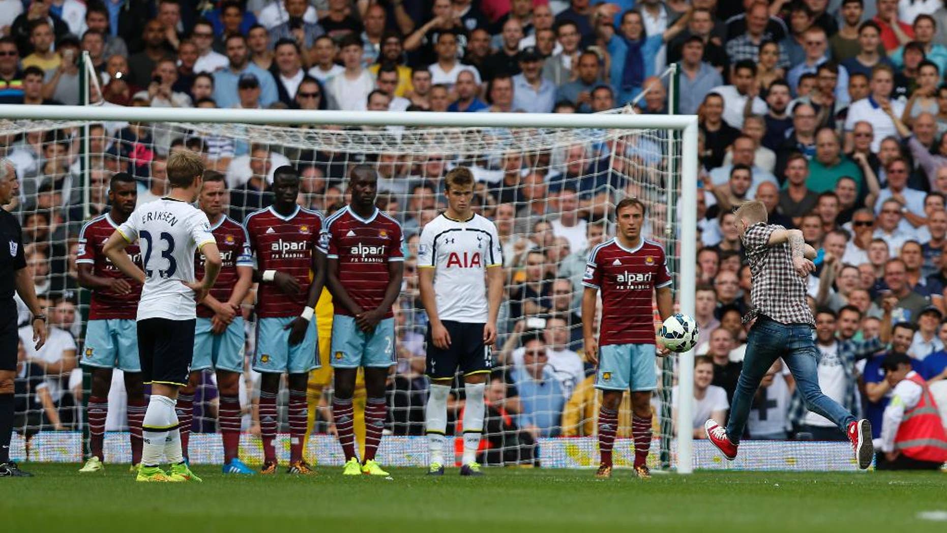 A supporter runs onto the pitch and kicks the ball set up for a Tottenham Hotspur's free kick against West Ham United during their English Premier League soccer match at Upton Park, London, Saturday, Aug. 16, 2014. (AP Photo/Sang Tan)
