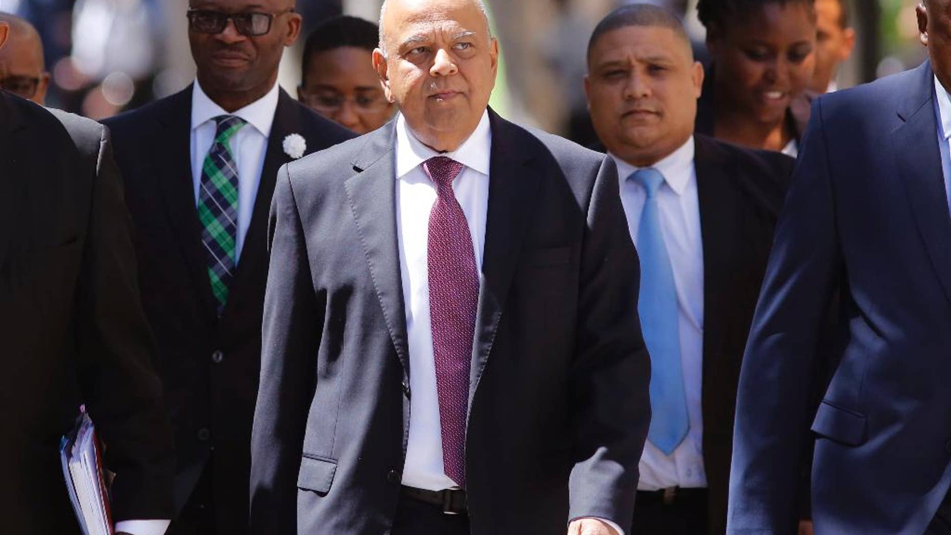 FILE -- In this Wednesday, Feb. 22, 2017 file photo South Africa's finance minister Pravin Gordhan, center, arrives at the South African Parliament to deliver the annual Budget speech in Cape Town, South Africa. Gordhan returned to Johannesburg on Tuesday, March 28, 2017, after being abruptly ordered to pull out of a trade promotion trip to the Britain and the United States, fuelling investor fears that he is about to be fired by President Jacob Zuma. (AP Photo/Schalk van Zuydam, File)