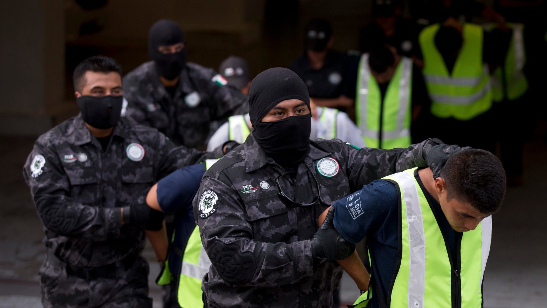 Municipal police officers suspected of involvement in the disappearance of 43 students in Guerrero State, are marched to waiting transport at the Mexican attorney generals' organized crime unit headquarters, in Mexico City, Friday, Oct. 17, 2014. Mexico's attorney general announced Friday that federal authorities had arrested the leader of the Guerrero Unidos cartel, as well as 36 police officers from two different cities, in connection with the slaying of six people, three of them students, and the disappearance of 43 other students. (AP Photo/Rebecca Blackwell)