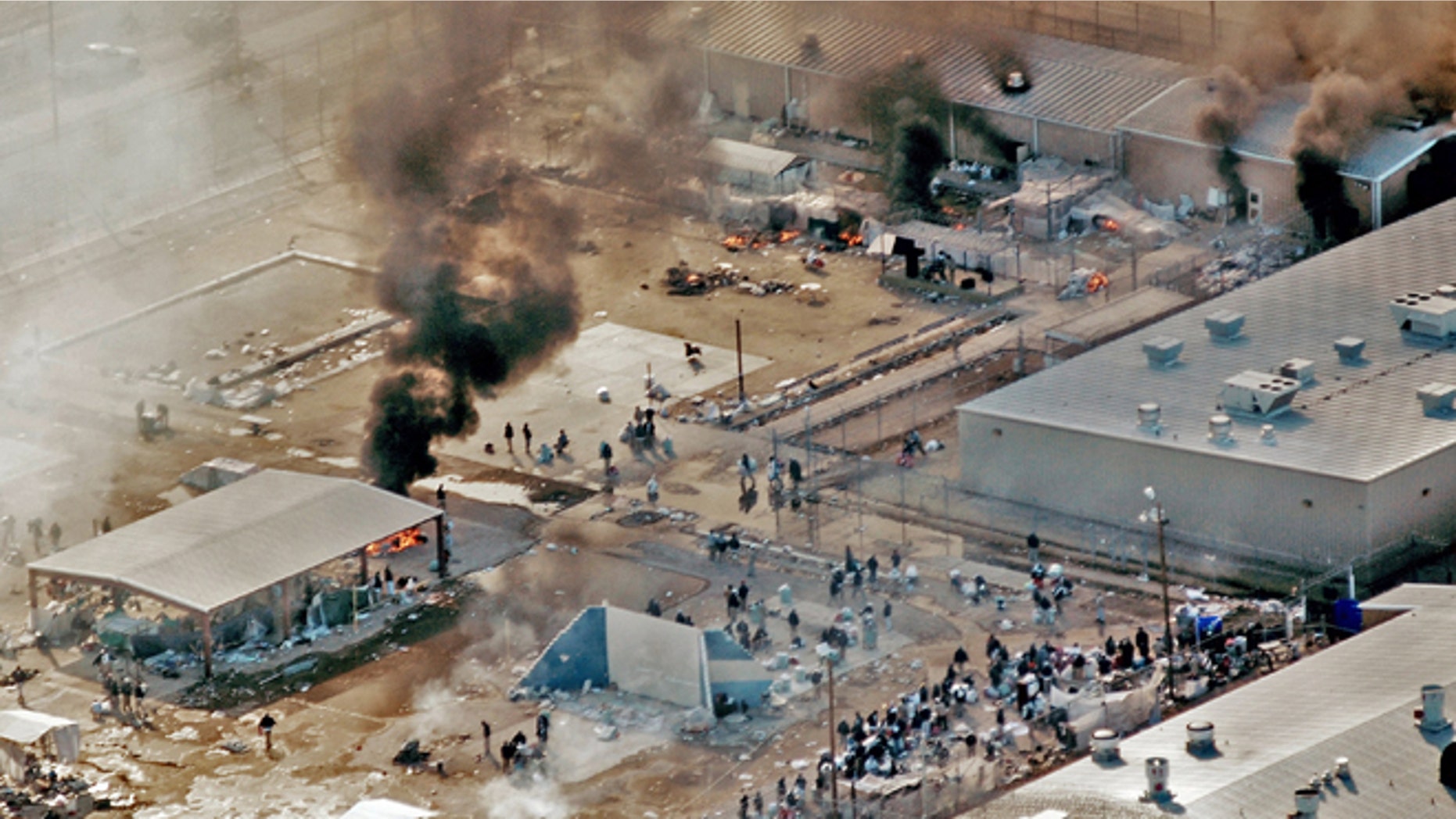FILE - In this Thursday, Feb. 5, 2009 file photo, plumes of smoke rise from the yard and recreation building of Reeves County Detention Center 1 unit in Pecos, Texas. The fires came five days after inmates set fires to other parts of the RCDC I and II units during a riot blamed on complaints about inadequate health care and food. A Justice Department Inspector General report released Thursday, April 23, 2015, was critical of the operation at the the 2,400-bed facility that primarily houses "low-level" immigrants in the country illegally. (AP Photo/Pecos Enterprise, Smokey Briggs, file)