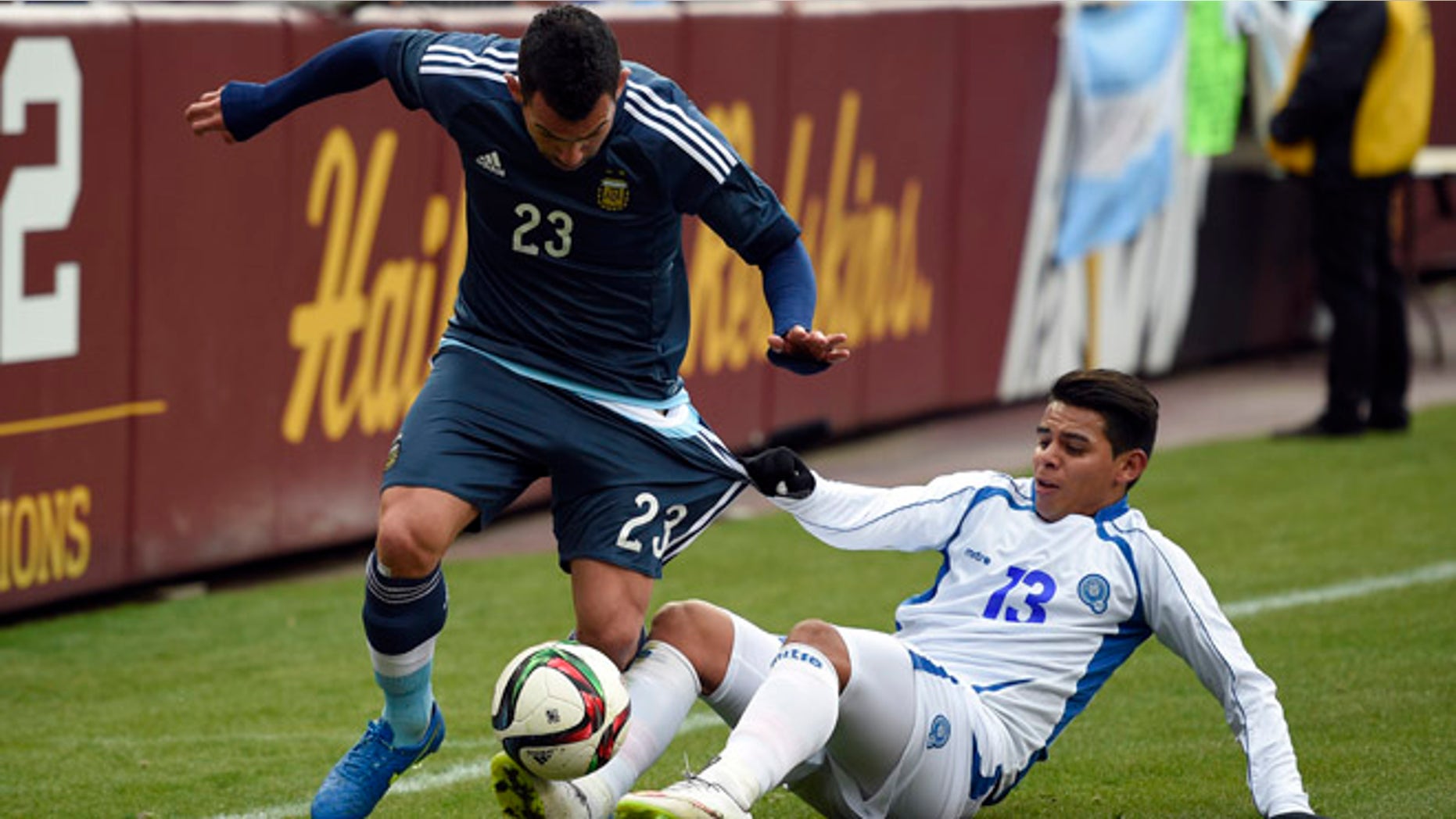 El Salvador's Alexander Larin (13) pulls on the shorts of Carlos Tevez (23) during the first half of an international friendly soccer game Saturday, March 28, 2015, in Landover, Md. (AP Photo/Nick Wass)
