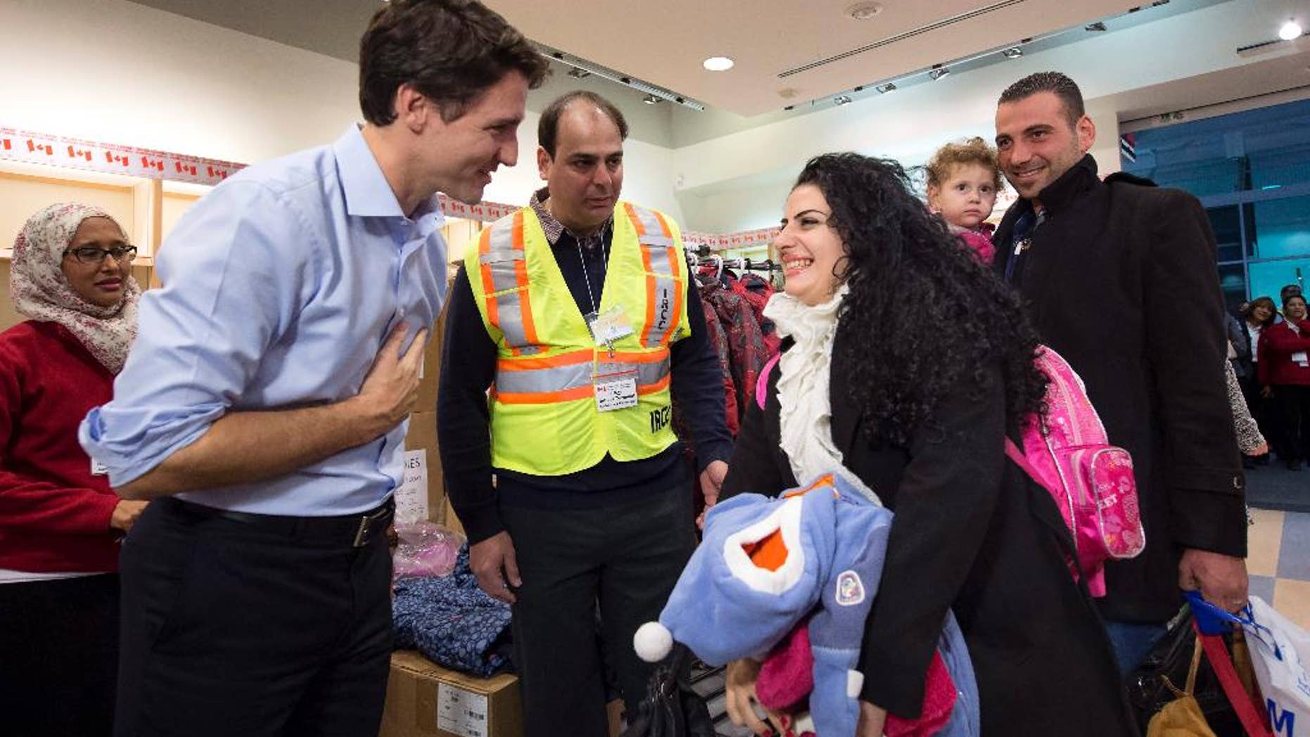FILE - In this Dec. 11, 2015 file photo, Prime Minister Justin Trudeau, left, greets Georgina Zires, center, Madeleine Jamkossian, second right, and her father Kevork Jamkossian, refugees fleeing from Syria, as they arrive at Pearson International airport, in Toronto. Trudeau has a message for refugees rejected by U.S. President Donald Trump: Canada will take you. He also intends to talk to Trump about the success of Canada’s refugee policy. Trudeau reacted to Trump’s ban of Muslims from certain countries by tweeting Saturday: “To those fleeing persecution, terror & war, Canadians will welcome you, regardless of your faith. Diversity is our strength #WelcomeToCanada.” (Nathan Denette/The Canadian Press via AP, File)