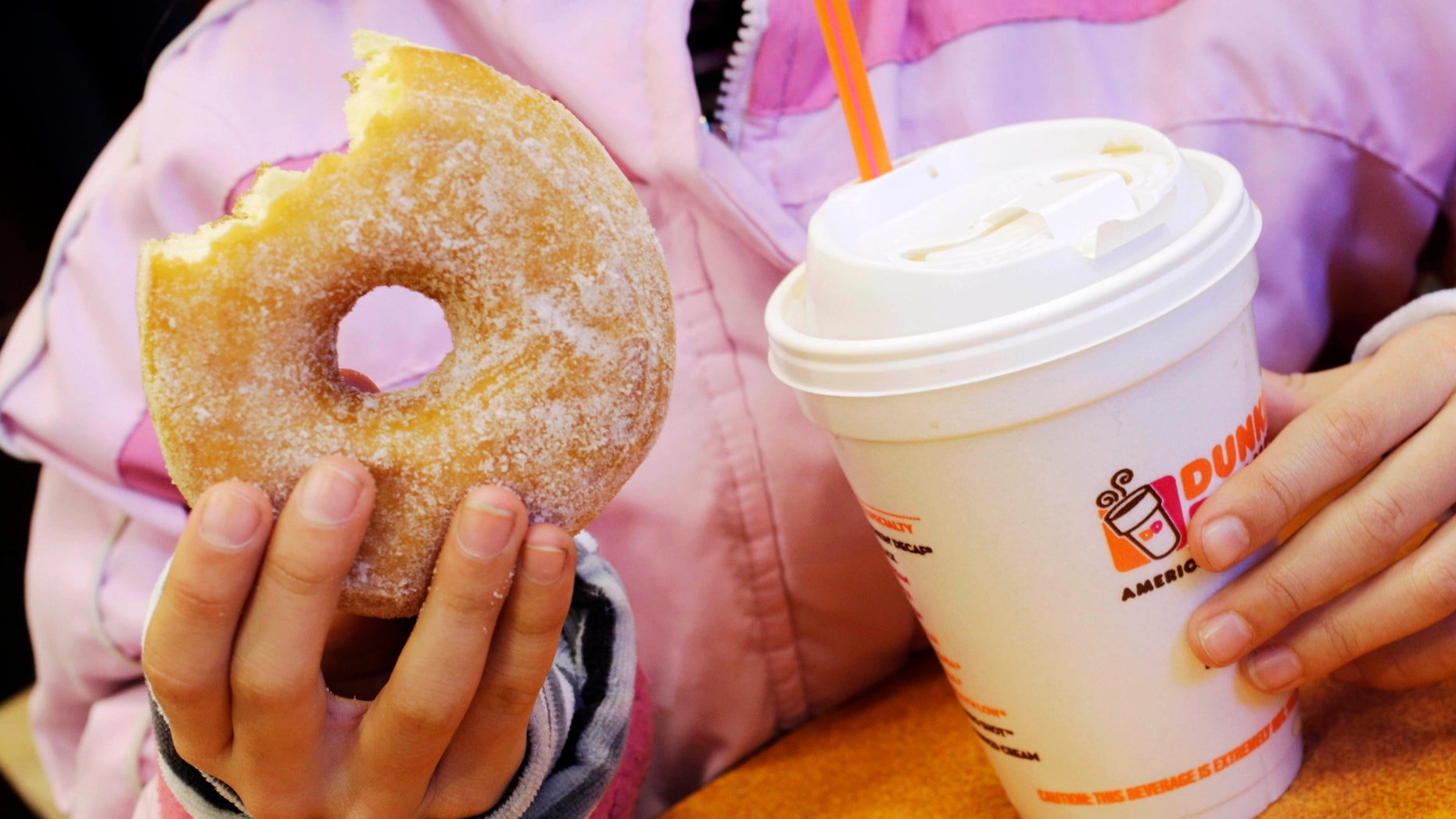FILE - In this Feb. 14, 2013 file photo, a girl holds a beverage, served in a foam cup, and a donut at a Dunkin' Donuts in New York. The New York City Council's sanitation committee has a hearing set for Monday, Nov. 25, 2013, on proposals to ban plastic-foam food containers or explore recycling them. (AP Photo/Mark Lennihan, File)