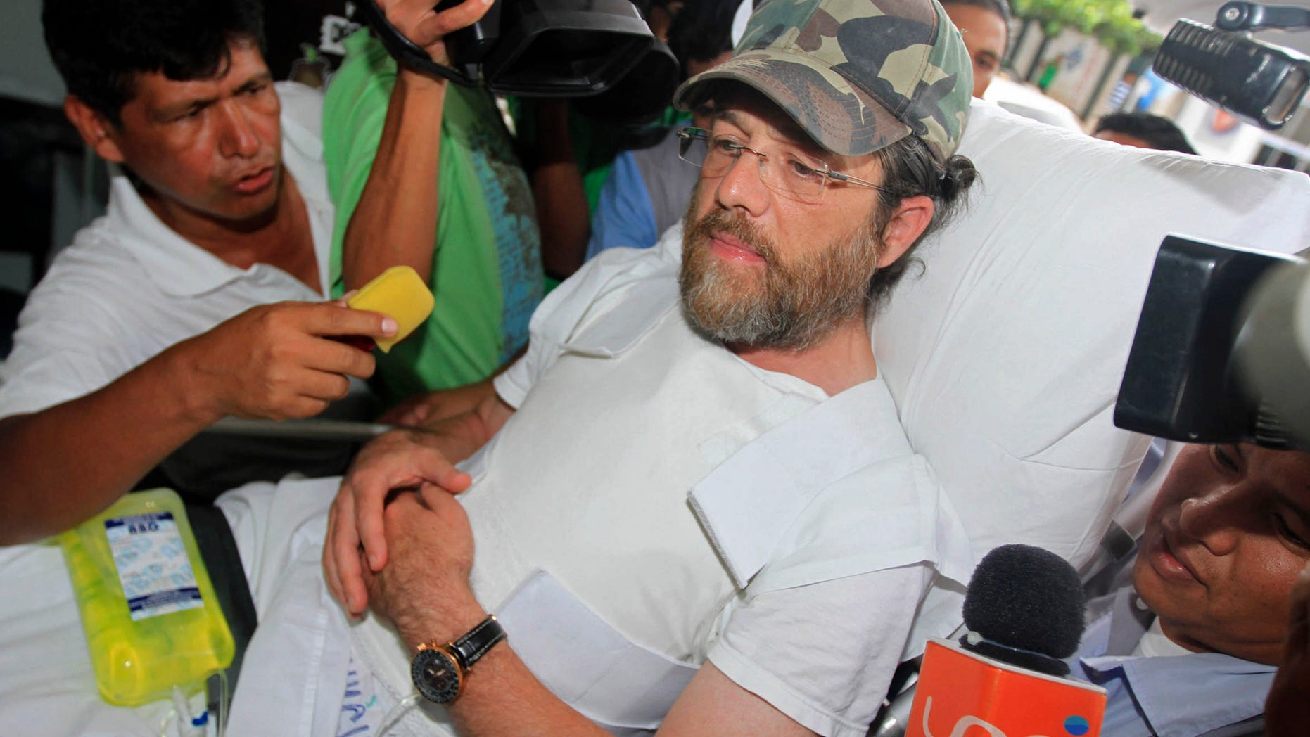 Dec. 11, 2012: Members of the press surround U.S. businessman Jacob Ostreicher as he arrives in a hospital bed wearing a flak jacket to his court hearing in Santa Cruz, Bolivia.