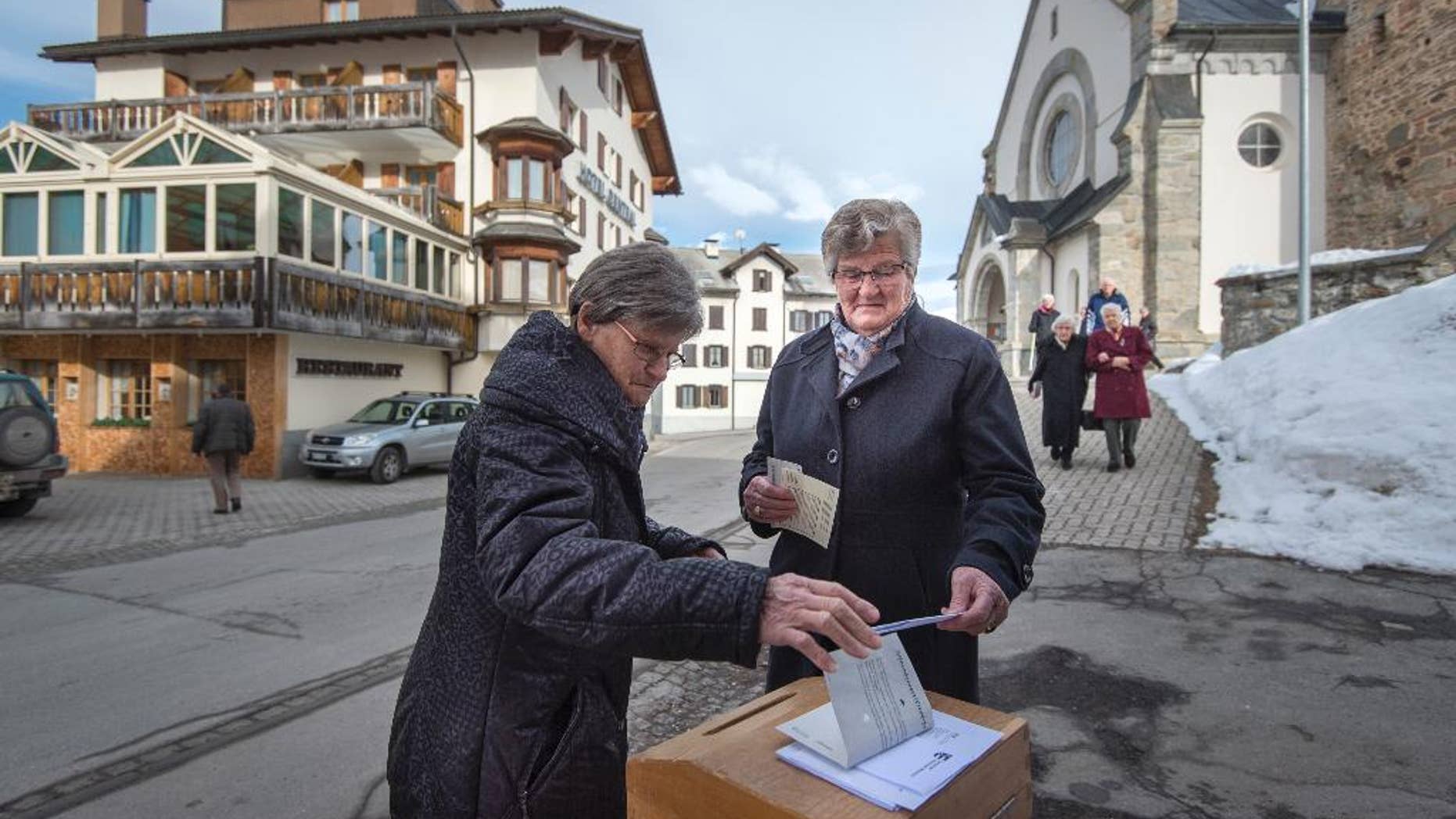 Swiss voters cast their ballot in Obersaxen, Switzerland, Sunday Feb. 12, 2017. Swiss voters were deciding Sunday whether to make it easier for "third-generation foreigners" to get Swiss citizenship and whether to lock in competitive low tax rates for foreign companies in Switzerland. (Benjamin Manser/Keystone via AP)