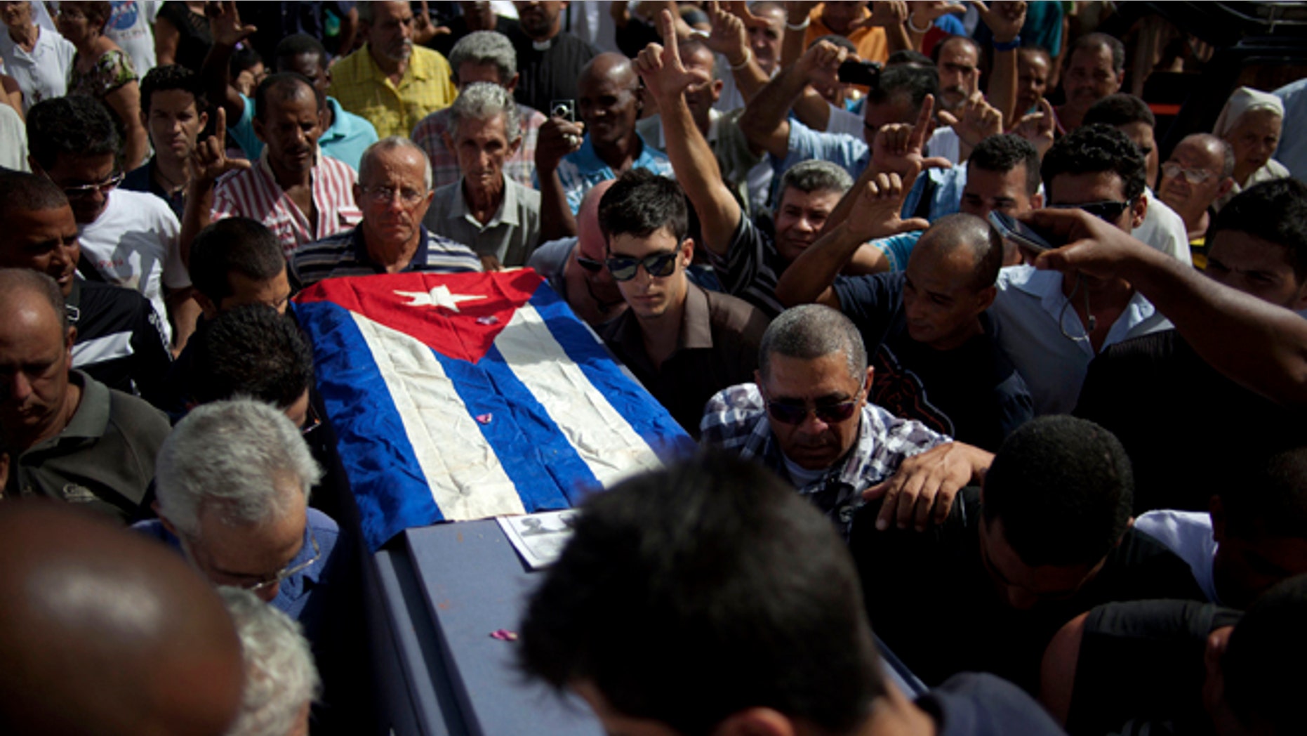 Friends and family of the late Cuban activist Oswaldo Paya carry his flag draped coffin during his burial at a cemetery in Havana, Cuba, Tuesday, July 24, 2012. Paya, 60, gained international fame as the lead organizer of the Varela Project, a signature-gathering drive asking authorities for a referendum on guaranteeing rights such as freedom of speech and assembly. The initiative launched a decade ago was seen as the biggest nonviolent campaign to change the system Fidel Castro established after the 1959 Cuban revolution. Paya died on Sunday, July 22, 2012 in a car crash. (AP Photo/Ramon Espinosa)