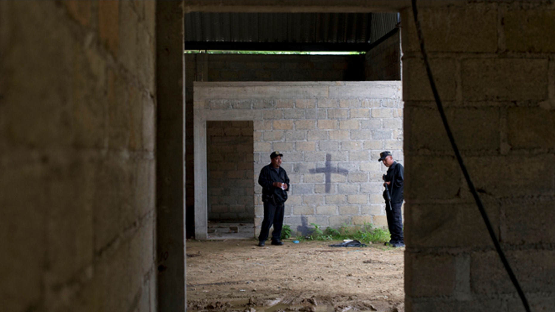 FILE - In this Thursday, July 3, 2014, file photo, state police stand inside a warehouse where a black cross covers a wall near blood stains on the ground, after a shootout between Mexican soldiers and alleged criminals on the outskirts of the village of San Pedro Limon, in Mexico state, Mexico. It was confirmed on Monday, Oct. 5, 2015, that a Mexican judge ruled that there is insufficient evidence to try four of the seven soldiers charged in the case of 22 suspects killed in 2014, some of whom were apparently shot after they surrendered. (AP Photo/Rebecca Blackwell, File)