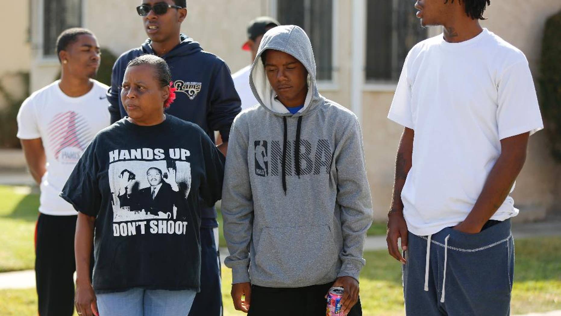 Neighbors and members of the community gather around a makeshift memorial to Carnell Snell Jr. on Sunday.