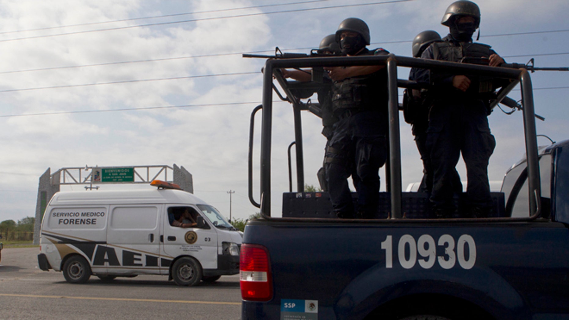 Federal police on a vehicle guard one of the three forensic trucks where several bodies were placed after dozens of bodies, some of them mutilated, were found on a highway connecting the northern Mexican metropolis of Monterrey to the U.S. border found in the Km 47 of the Reynosa-Cadereyta road in the town of San Juan near the city of Monterrey, Mexico, Sunday, May 13, 2012. (AP Photo/Christian Palma)
