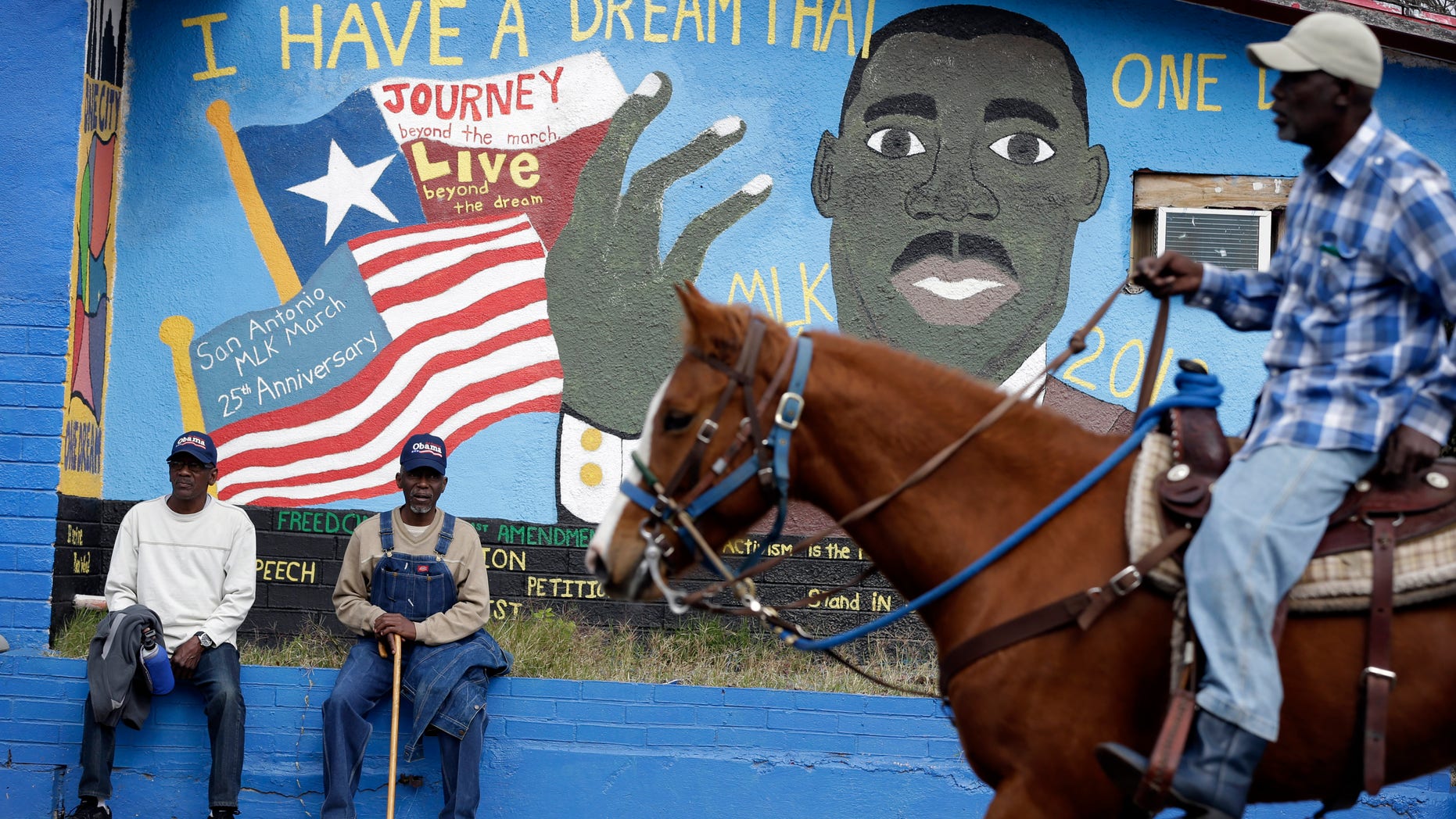 Riders pass a mural as they take part in a march honoring Martin Luther King Jr., Monday, Jan. 21, 2013, in San Antonio. The nation honors civil rights leader Martin Luther King Jr. on Monday, the same day as it celebrates the inauguration of the first black president to his second term. (AP Photo/Eric Gay)