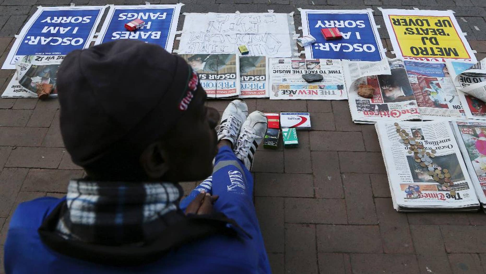 A vendor sells newspaper with headlines on Oscar Pistorius ouside the high court in Pretoria, South Africa, Tuesday, April 8, 2014. Pistorius, who is charged with murder for the shooting death of his girlfriend, Reeva Steenkamp, on Valentines Day in 2013, was testifying for a second day at his murder trial Tuesday, answering questions from his defense lawyer. (AP Photo/Themba Hadebe)