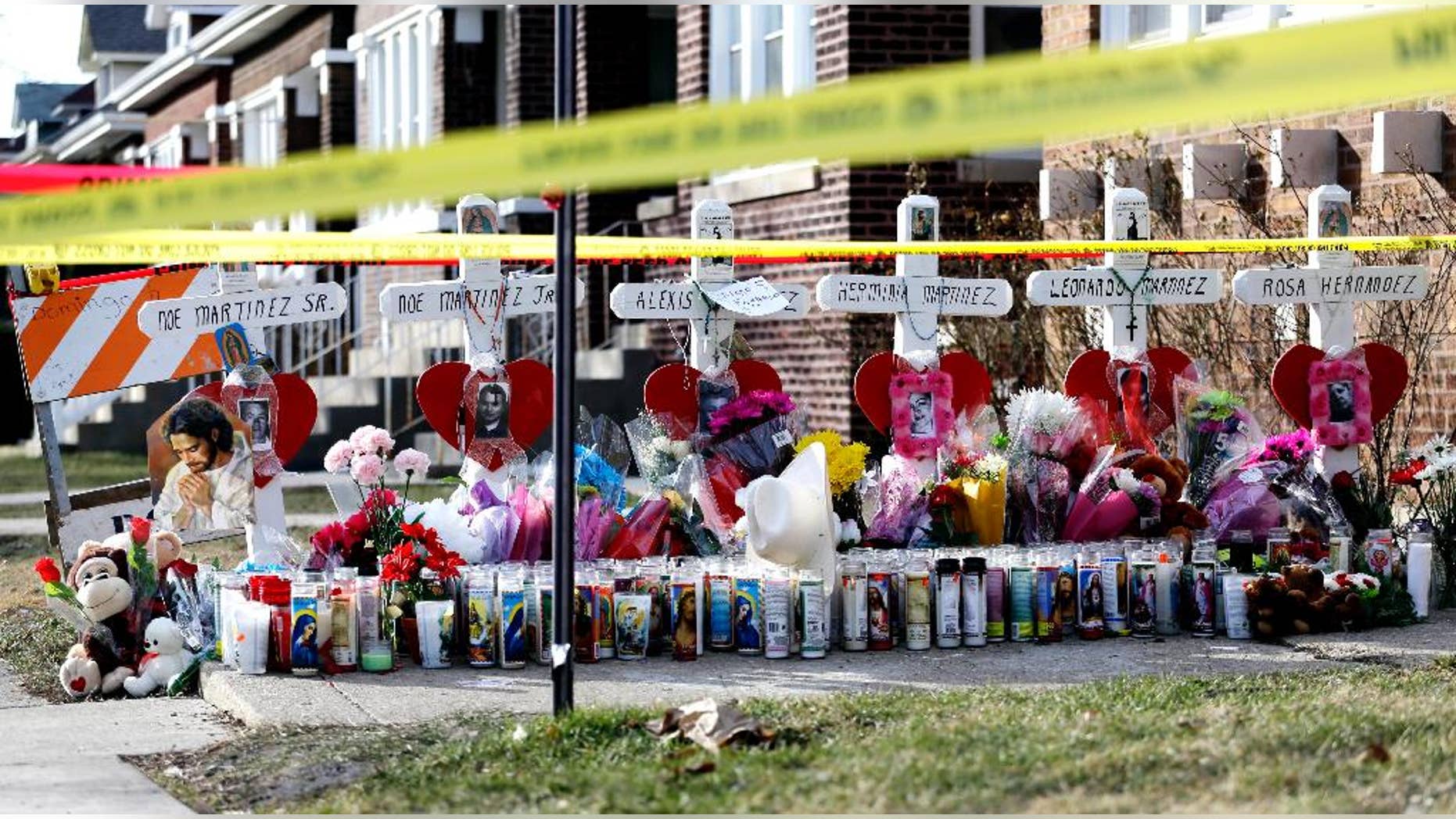 FILE - In this Feb. 7, 2016 file photo, crosses and crime scene tape are seen outside a home in Chicago where six bodies, four adult and two children, were found Feb. 4. A new report by the Cook County medical examiner on Tuesday, April 19, 2016, reveals details of the autopsies of three of the victims. Autopsies for the other three victims were previously released. (AP Photo/Nam Y. Huh, File)