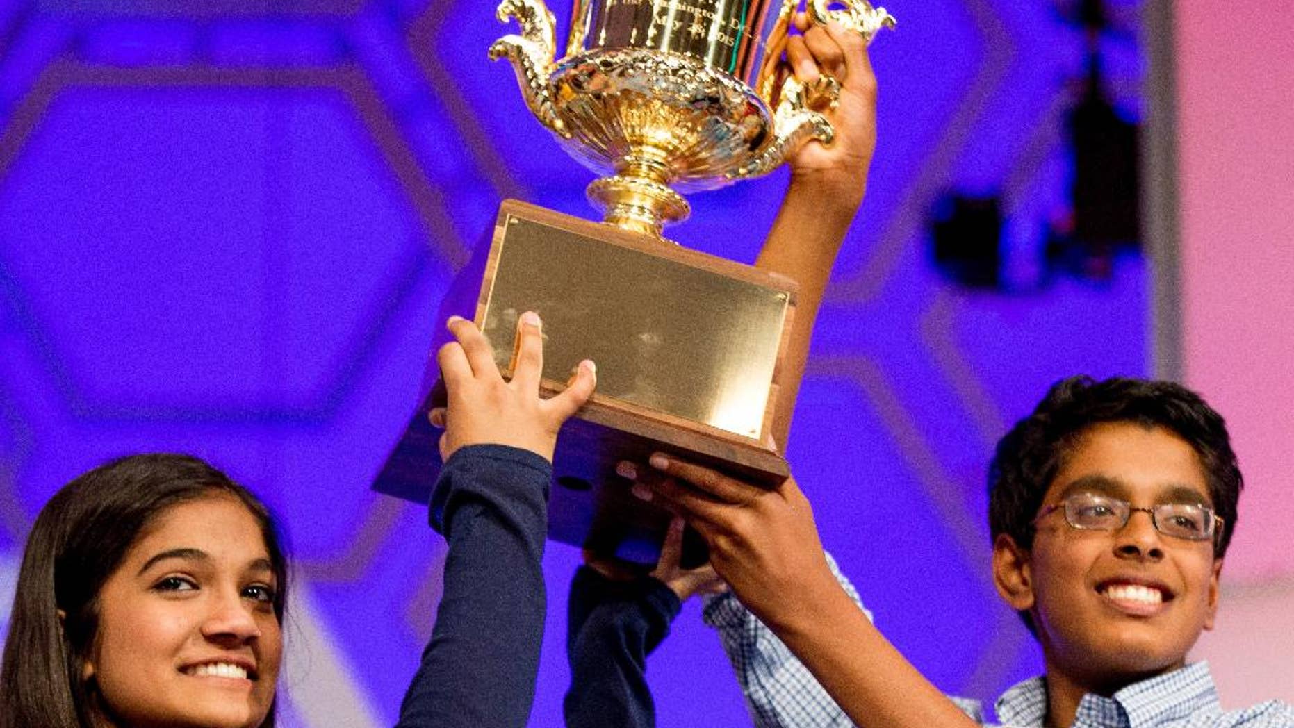 FILE - In this May 28, 2015, file photo, Vanya Shivashankar, 13, left, of Olathe, Kan., left, and Gokul Venkatachalam, 14, of St. Louis, hold up the trophy as co-champions after winning the finals of the Scripps National Spelling Bee in Oxon Hill, Md. The Scripps National Spelling Bee is adding a new wrinkle in 2017 in yet another attempt to stop a streak of ties for the championship. This year, the top spellers will sit for a written tiebreaker test before they begin spelling words in the primetime finale. The results will be revealed only if two or three spellers get through the final rounds unscathed. (AP Photo/Andrew Harnik, File)