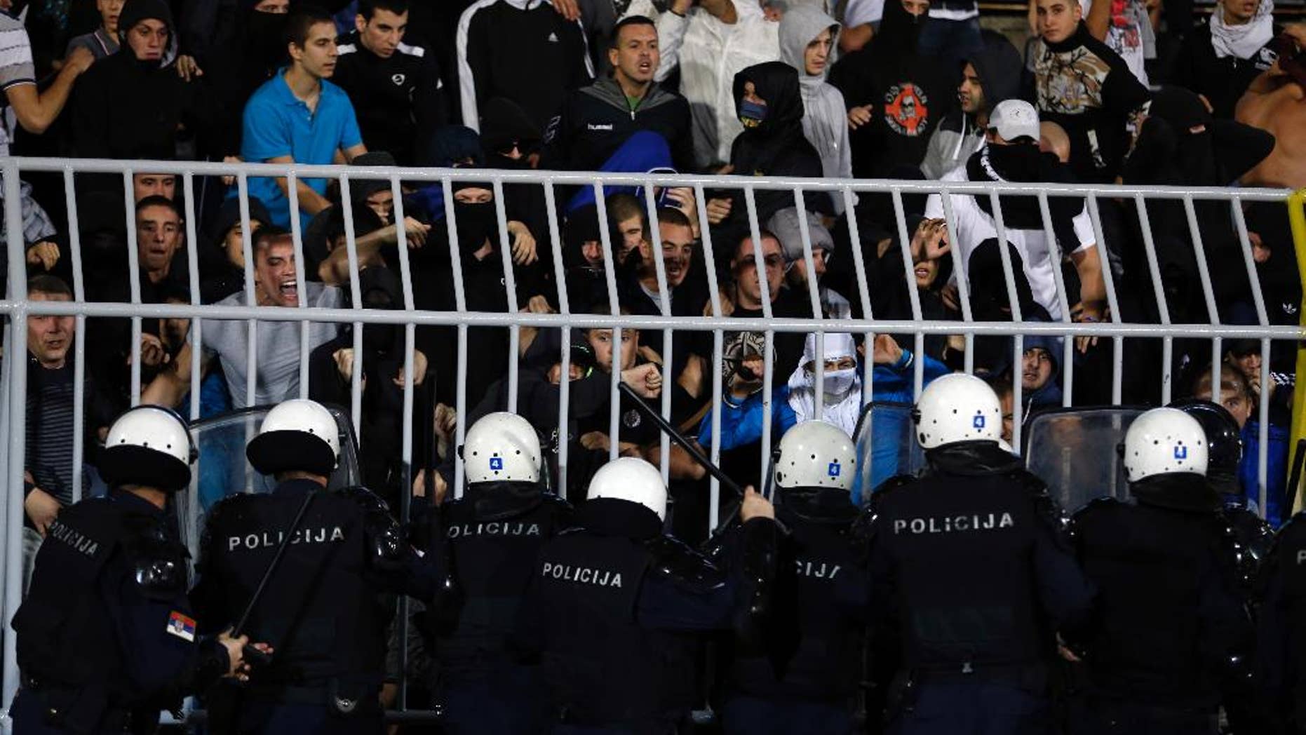 Serbian riot police officers clash with Serbian national team supporters during the Euro 2016 Group I qualifying match between Serbia and Albania at the Partizan stadium in Belgrade, Serbia, Tuesday, Oct. 14, 2014. The 2016 European Championship qualifier between Serbia and Albania was abandoned on Tuesday after skirmishes broke out on the pitch involving players and fans over an Albanian flag that was flown above the stadium by a drone. (AP Photo/Marko Drobnjakovic)