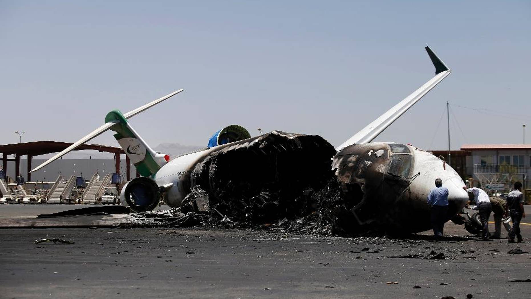 Officials of Felix Airways, a domestic airline, inspect a plane destroyed by Saudi-led airstrikes, at the Sanaa International airport, in Yemen, Wednesday, April 29, 2015. Saudi-led coalition warplanes pounded Shiite rebels and their allies overnight and throughout the day on Tuesday in the Yemeni capital. Around midday, airstrikes hit Sanaa International airport, setting a plane owned by a private company on fire, according to a statement released by the Shiite rebels, known as Houthis. (AP Photo/Hani Mohammed)