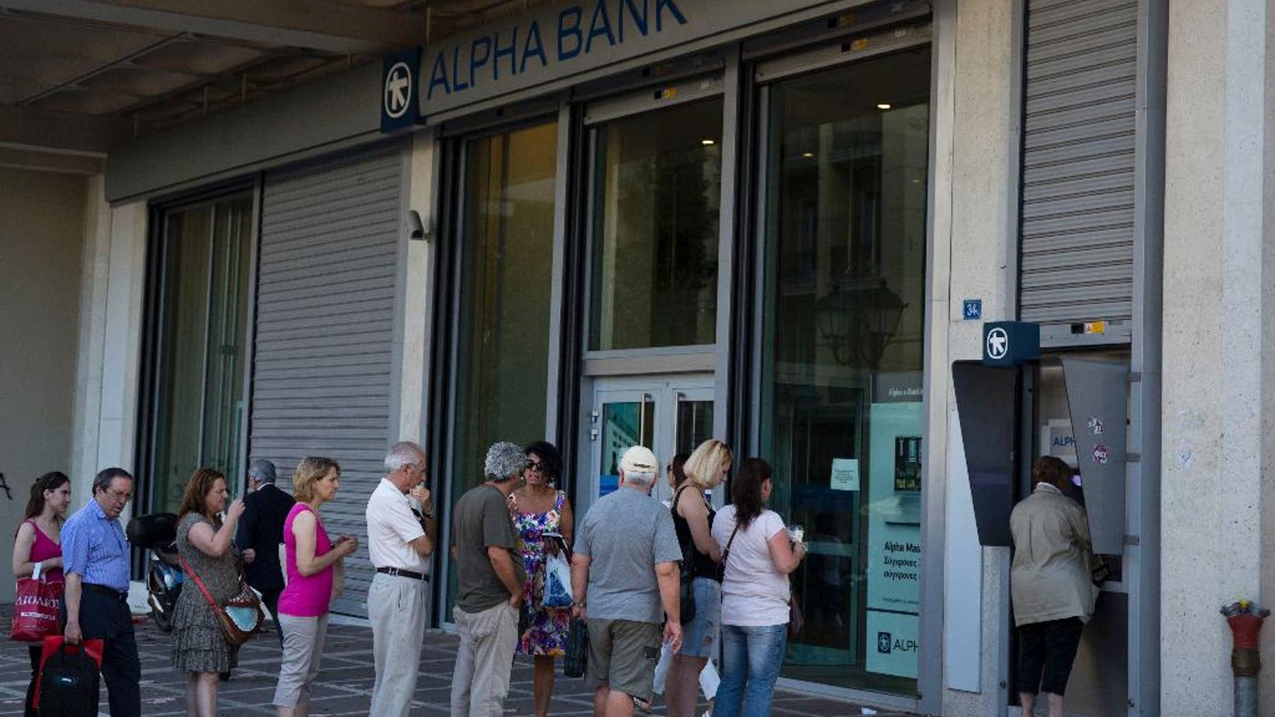 People line up to use an ATM machine outside a bank in Athens, on Monday, July 6, 2015. Greece’s Finance Minister Yanis Varoufakis has resigned following Sunday’s referendum in which the majority of voters said “no” to more austerity measures in exchange for another financial bailout. (AP Photo/Petros Giannakouris)