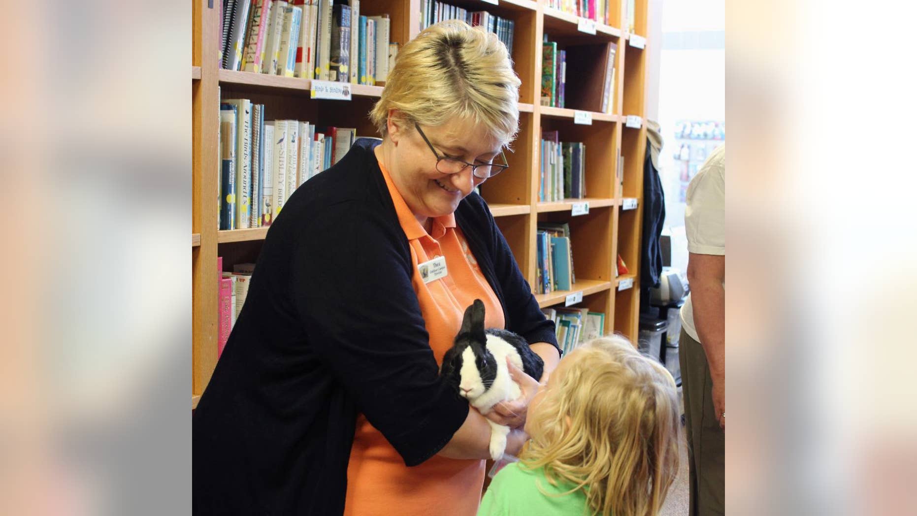 In this May 25, 2016, photo, South Dakota wildlife official Thea Miller, the director of the Outdoor Campus in Sioux Falls, S.D., holds a rabbit while children pet it and listen to her talk about the need to avoid rescuing healthy baby wild animals. Miller has started a social media campaign to remind people to leave baby wild animals alone. (AP Photo/Regina Garcia Cano)