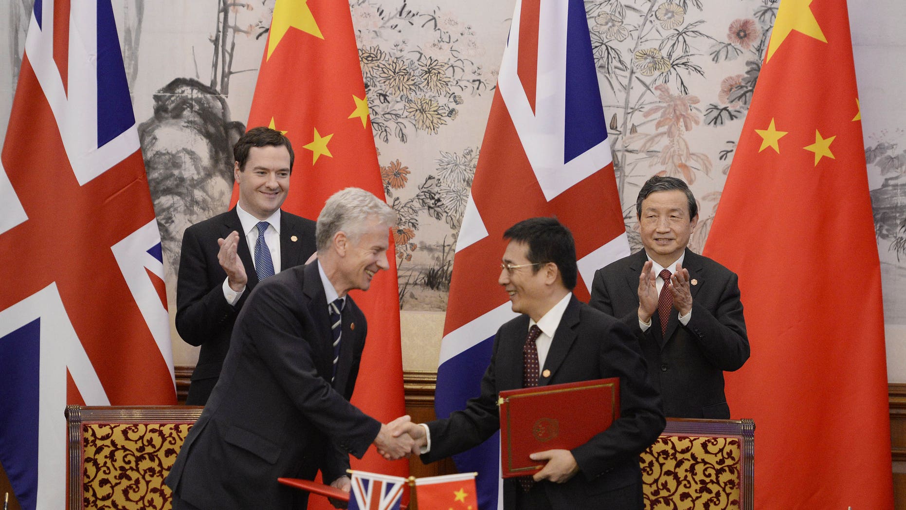 Britain's Chancellor of the Exchequer George Osborne, left, and Chinese Vice premier Ma Kai applaud as their officials shake hands after exchanging signed documents of their agreement during a signing ceremony at the Diaoyutai Guesthouse in Beijing Tuesday, Oct. 15, 2013. (AP Photo/Kota Endo, Pool)
