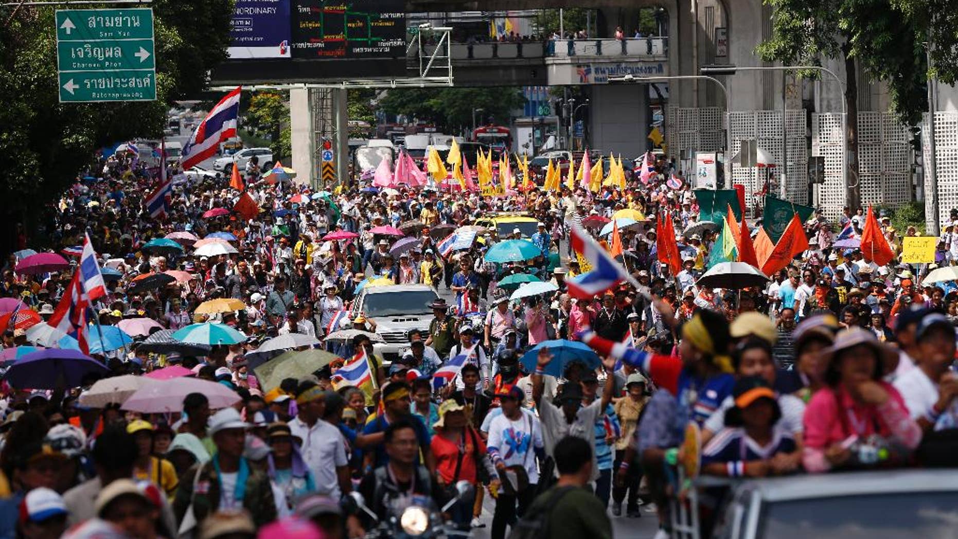 Anti-government protesters march through a main road in downtown Bangkok, Thailand, Friday, May 9, 2014. Thailand's anti-graft commission indicted ousted Prime Minister Yingluck Shinawatra on Thursday on charges of dereliction of duty in overseeing a widely criticized rice subsidy program, a day after a court forced her from office. Yingluck was accused of allowing the rice program, a flagship policy of her administration, to proceed despite advice that it was potentially wasteful and prone to corruption. (AP Photo/Vincent Thian)