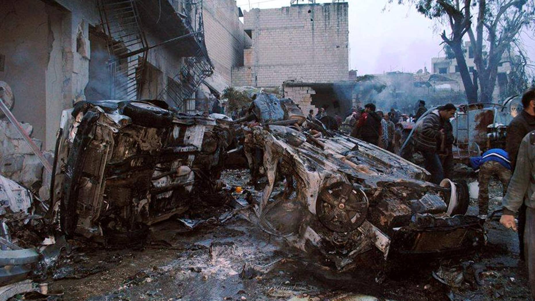 March 1, 2014: This photo, provided by the anti-government activist group Coordination Committee In Kfar Takharim, which has been authenticated based on its contents and other AP reporting, shows Syrian citizens inspecting destroyed cars and buildings which were attacked by a Syrian government forces airstrike in the town of Kfar Takharim in the northwest province of Idlib, Syria.