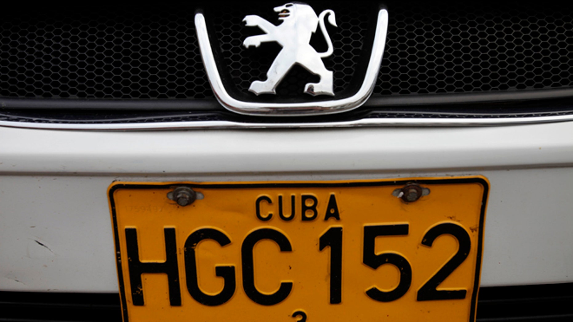 FILE - This Dec. 19, 2013 file photo shows a detail of a license plate on a Peugeot as it drives by in Havana, Cuba. Cuban authorities reported on Monday, June 30, 2014 that auto dealerships have sold just 50 automobiles and four motorcycles across the country in the nearly six months since a new law took effect letting islanders buy vehicles without a special permit for the first time in decades. Many Cubans were delighted when the new rules were announced in December 2013, and then left aghast by the sticker prices once they took effect. Most Cubans earn about $20 a month. (AP Photo/Franklin Reyes, File)