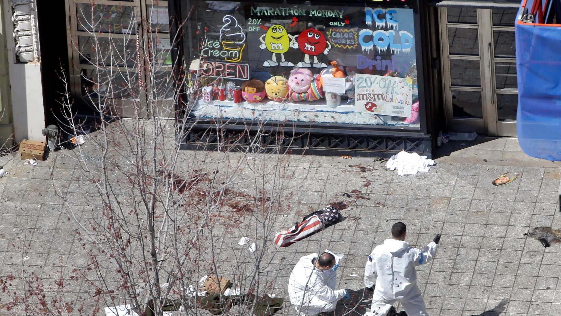 Two men in haz-mat suits investigate the scene of the first bombing on Boylston Street in Boston Tuesday, April 16, 2013 near the finish line of the 2013 Boston Marathon, a day after two blasts nearby killed three and injured over 170 people. (AP Photo/Elise Amendola)
